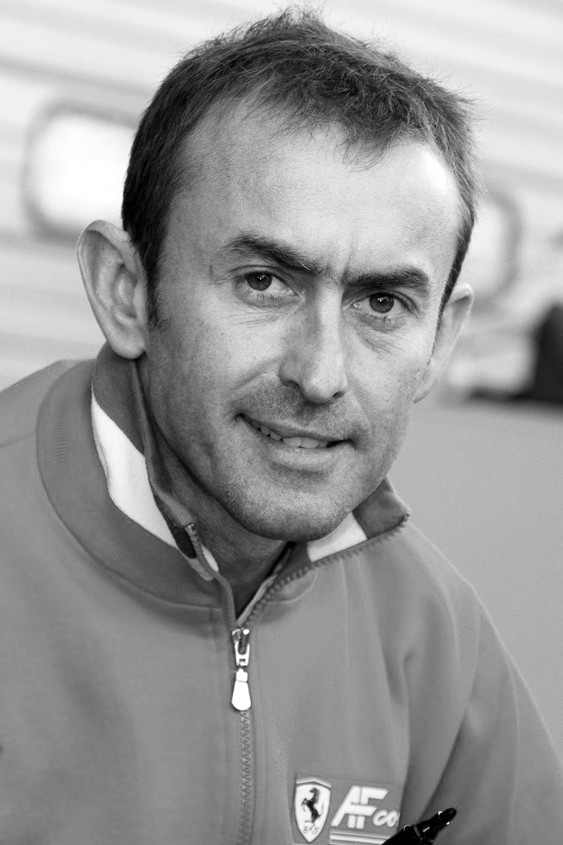 Head-and-shoulders portrait of a man with short hair, smiling slightly at the camera, in a zipped team top with a striped collar.